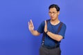 Portrait of nervous anxious young Asian man make stop don\'t move gesture over purple uebackground