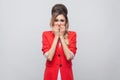 Portrait of nervous beautiful business lady with hairstyle and makeup in red fancy blazer, standing biting her nails and looking Royalty Free Stock Photo