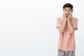 Portrait of nervous and scared young asian boy in striped t-shirt biting fingers looking at upper left corner insecure Royalty Free Stock Photo