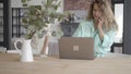 Portrait nervous young mother in front of laptop trying to talk by cell phone while her teen sons running araund playing