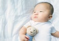 Portrait of a newborn Asian baby boy on the bed , Charming Fat baby 5 month old lies in bed and the doll ,enjoy and happy,soft and Royalty Free Stock Photo