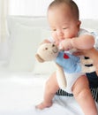 Portrait of a newborn Asian baby boy on the bed , Charming Fat baby 5 month old lies in bed and the doll ,enjoy and happy,soft and Royalty Free Stock Photo