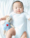 Portrait of a newborn Asian baby boy on the bed , Charming Fat baby 5 month old lies in bed and the doll ,enjoy and happy,soft and Royalty Free Stock Photo