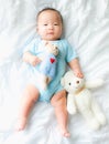 Portrait of a newborn Asian baby boy on the bed with a doll , Charming Royalty Free Stock Photo