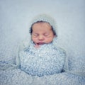 Portrait of newborn baby boy wrapped in blue wrap withknitted wool cap on head Royalty Free Stock Photo
