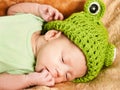 Portrait of a newborn baby sleeping on a brown plaid in a green frog hat Royalty Free Stock Photo