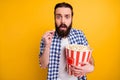 Portrait of nice attractive worried scared addicted bearded guy in checked shirt overeating popcorn junk snack watching