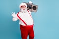 Portrait of nice bearded cheerful funky funny glad big belly Santa carrying tape player having fun isolated over bright
