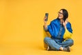 Portrait of nice beautiful lovely glad cheerful woman holding in hands Ukrainian flag having fun isolated over yellow background. Royalty Free Stock Photo