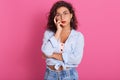 Portrait of nice cute attractive winsome delicate creative wavy haired girl in blue shirt and jeans, holding her finger onher Royalty Free Stock Photo
