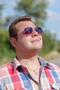 Portrait of a nice friendly smiling guy in sunglasses. Man portrait in nature. The guy looks at the sun in glasses