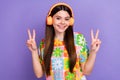 Portrait of nice good mood person long hairstyle wear stylish t-shirt showing v-sign in headphones isolated on purple Royalty Free Stock Photo