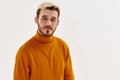 portrait of a nice guy with a beard blond orange sweater light background