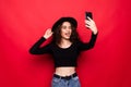 Portrait of attractive woman wearing sunhat taking making selfie isolated red background Royalty Free Stock Photo