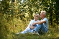 Portrait of nice mature couple sitting on green grass in summer park Royalty Free Stock Photo