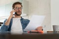 Smiling man, he is sitting at a table, talking on the phone with his laptop, notebook and glasses in front of him Royalty Free Stock Photo