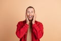 Portrait of nice young man hands touch cheeks wear red shirt isolated on beige color background