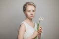 Portrait of nice young woman with blonde updo hair and white flowers in hands on white background