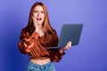 Portrait of nice young woman hold laptop stare wear brown shirt isolated on purple color background Royalty Free Stock Photo