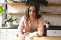 Portrait of non-binary trans woman with coffee cup smiling in the kitchen at home