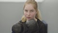 Portrait of non-confident blond woman in boxing gloves imitating dodging blows in the gym close up. Cute newbie