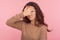 Portrait of nosy prying inquisitive young woman with brunette hair peeking through fingers with curious expression Royalty Free Stock Photo