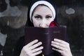 portrait of a nun in black clothes reading the bible and using a rose petal as a bookmark Royalty Free Stock Photo