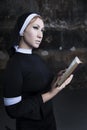 portrait of a nun in black clothes reading the bible and using a rose petal as a bookmark Royalty Free Stock Photo