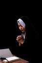 Portrait of nun is praying and reading scripture on black background Royalty Free Stock Photo