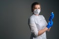 Portrait of nurse in blue gloves and face mask holding and filling up vaccine to syringe on black isolated background Royalty Free Stock Photo