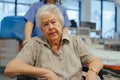 Portrait of nurse pushing senior patient in wheelchair across hospital corridor. Emotional support for elderly woman. Royalty Free Stock Photo