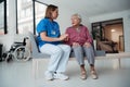 Portrait of nurse and senior patient talking in hospital corridor. Emotional support for elderly woman.