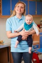 Portrait Of Nursery Worker Holding Baby