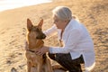 Portrait o happy attractive senior woman with her german shepard dog on the beach at autumn sunset Royalty Free Stock Photo