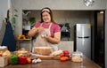 Portrait of obese woman cooking pizza in the kitchen, Raw pizza in the hands of a housewife. Homemade pizza cooking in the kitchen Royalty Free Stock Photo