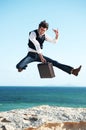 Portrait, ocean and jump with man, briefcase and excited with happiness, holiday and business. Person, employee and Royalty Free Stock Photo