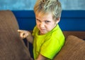 Portrait offended blond boy making freckles face in bad mood, angry points a finger. Funny photo, emotions gesture