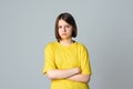 Portrait of a offended teen girl with crossed arms, standing over light grey background. Teen disappointment. Loneliness boredom
