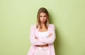 Portrait of offended timid girl with short blond hair, looking mad at someone, sulking and crossing arms over chest