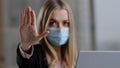 Portrait in office caucasian girl woman in medical face mask with laptop angry looking at camera puts palm forward no Royalty Free Stock Photo