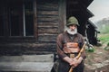 Old bearded forester with axe near wooden hut