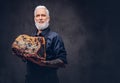 Tattooed elderly butcher with apron holding huge meat piece