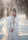 Portrait of an old-fashioned blonde woman in a vintage white dress in a winter forest. A girl with a high, old-fashioned Royalty Free Stock Photo