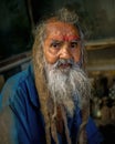 Portrait of an old Indian man with gray hair and beard in dirty clothes