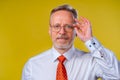 Portrait of an old man smiling, looking at camera, in studio, yellow backgroung Man in glasses portrait Royalty Free Stock Photo