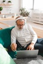 Portrait old senior elderly man with headphone listening to music on laptop at home - active senior people concept Royalty Free Stock Photo