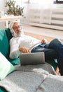 Portrait old senior elderly man with headphone listening to music on laptop at home - active senior people concept Royalty Free Stock Photo