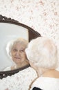 Portrait of old woman looking into a mirror at home Royalty Free Stock Photo