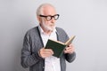 Portrait of old white hair optimistic man read book wear spectacles dark sweater isolated on grey background Royalty Free Stock Photo