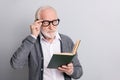 Portrait of old white hair serious man read book wear spectacles dark sweater isolated on grey background Royalty Free Stock Photo